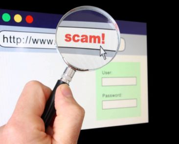 A hand holds a magnifying glass over the location bar of a browser, revealing the URL is a "scam".