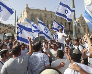 Israelis wave national flags during a Jerusalem Day march, in Jerusalem, Monday, May 10, 2021. Israeli police have changed the route of a contentious march by Jewish ultranationalists in Jerusalem, in an apparent attempt to avoid confrontations with Palestinian protesters. The original route had planned to go through Damascus Gate and into the Muslim Quarter of the Old City and on to the Western Wall. (AP Photo/Ariel Schalit)
