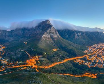 Table Mountain covered by its typical cloud table cloth and the twelve Apostles. Below on the left you can see Cape Town and the beautiful Camps Bay on the right. Taken right after sunset.