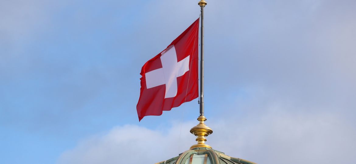 The flag of Switzerland flies on the dome of the Parliament Building (Bundeshaus), in Bern