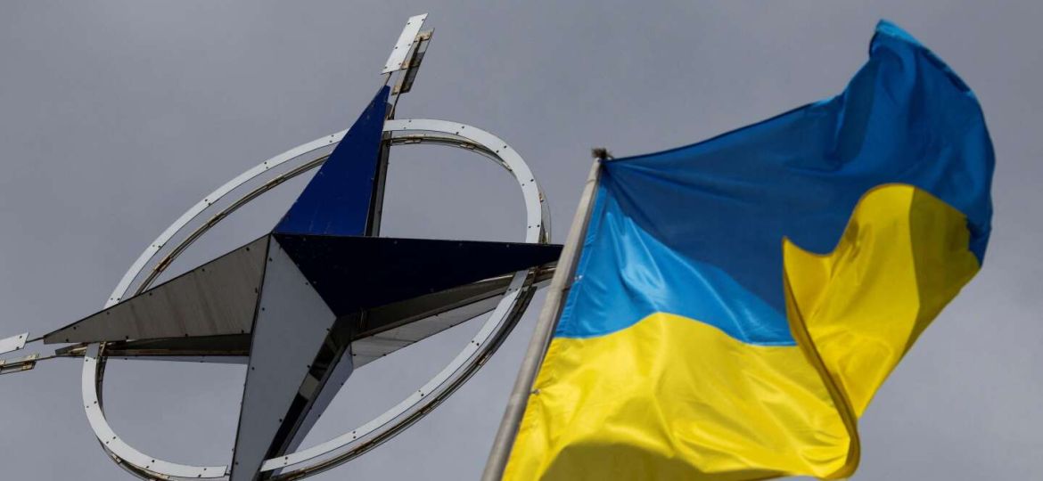 Ukrainian national flag rises in front of the NATO emblem in central Kyiv