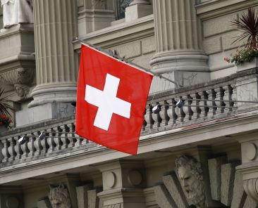 Swiss national flag fly outside the Federal Palace, Switzerland's parliament building, in Bern, Switzerland, on Wednesday, June 6, 2018. Photographer: Stefan Wermuth/Bloomberg