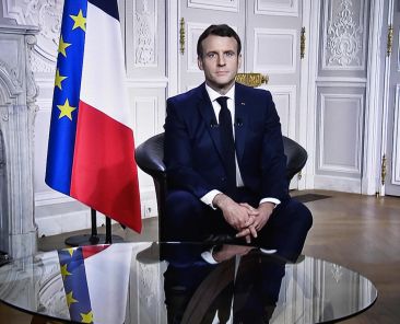 This photograph shows a television screen broadcasting French President Emmanuel Macron delivering his New Year wishes during an address to the nation from the Elysee Palace, in Paris, on December 31, 2020. (Photo by STEPHANE DE SAKUTIN / AFP)