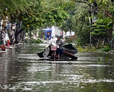 TOPSHOT - A woman collects debris on a flooded street after Super Typhoon Yagi hit Hai Phong, on September 8, 2024. Super Typhoon Yagi uproots thousands of trees, sweeps ships and boats out to sea and rips roofs off houses in northern Vietnam, after leaving a trail of destruction in southern China and the Philippines. (Photo by Nhac NGUYEN / AFP)