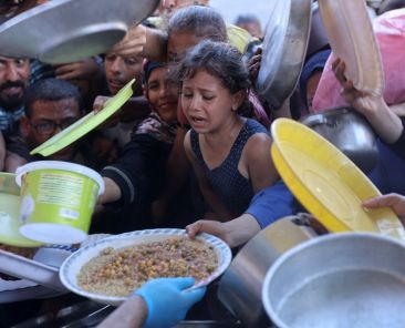 Palestinian children react as they are given a plate of food at a food distribution point, set up by young men from the Madhoun family in Beit Lahia, in the northern Gaza Strip on July 18, 2024, amid the ongoing conflict between Israel and the Palestinian Hamas militant group. UN rights experts on July 9, 2024, accused Israel of carrying out a "targeted starvation campaign" that has resulted in the deaths of children in Gaza. The UN has not officially declared a famine in the Gaza Strip. (Photo by Omar AL-QATTAA / AFP)